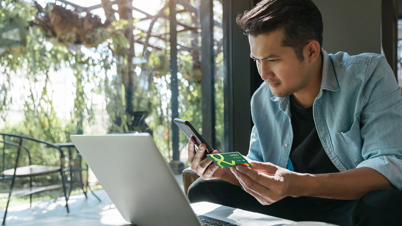 Man looking at phone and laptop