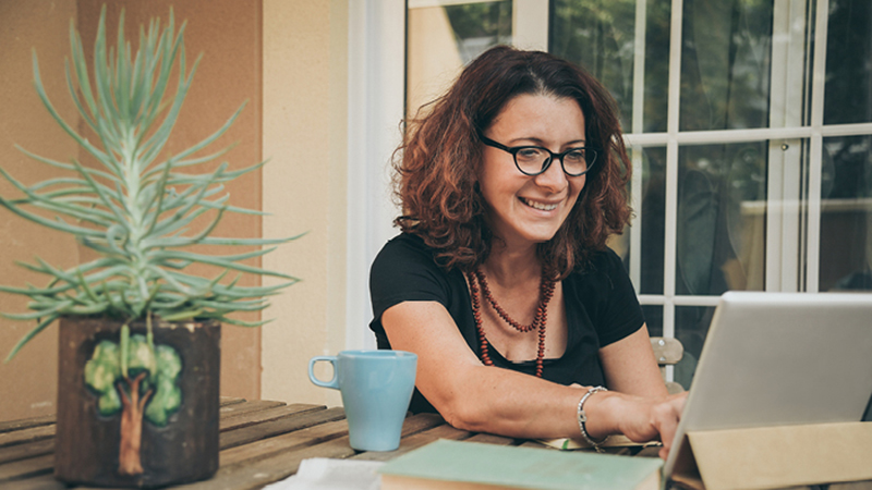 Smiling person sitting with tablet and mug