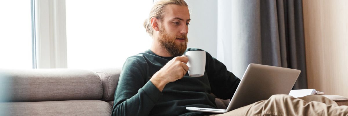 Person on sofa with laptop, holding a mug