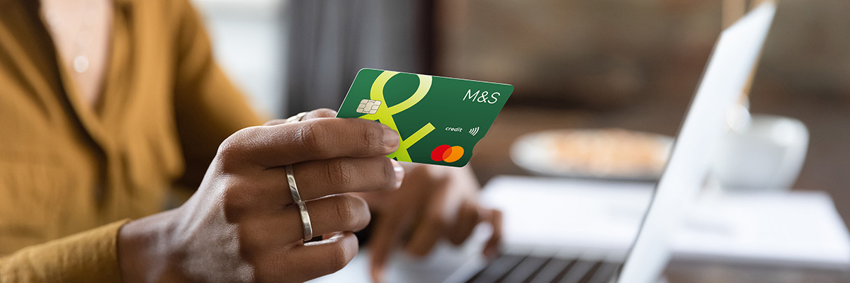 Close up of hand holding Credit Card over laptop