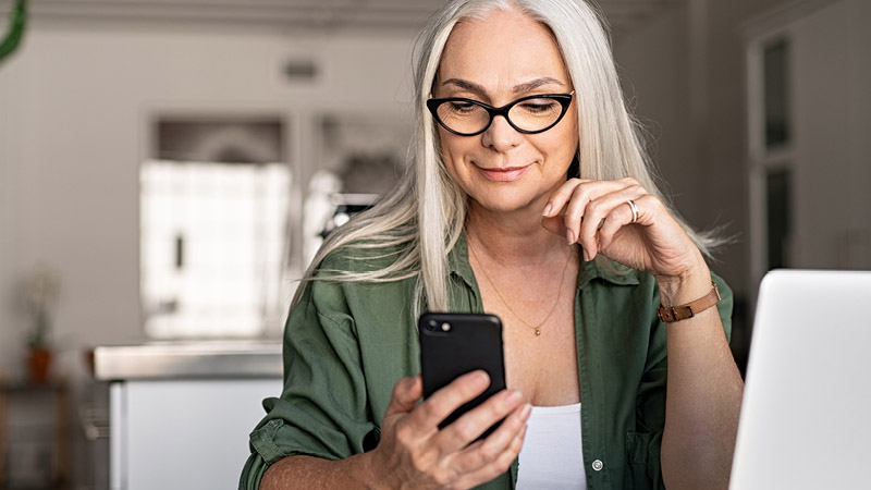 Lady smiling whilst using her mobile phone