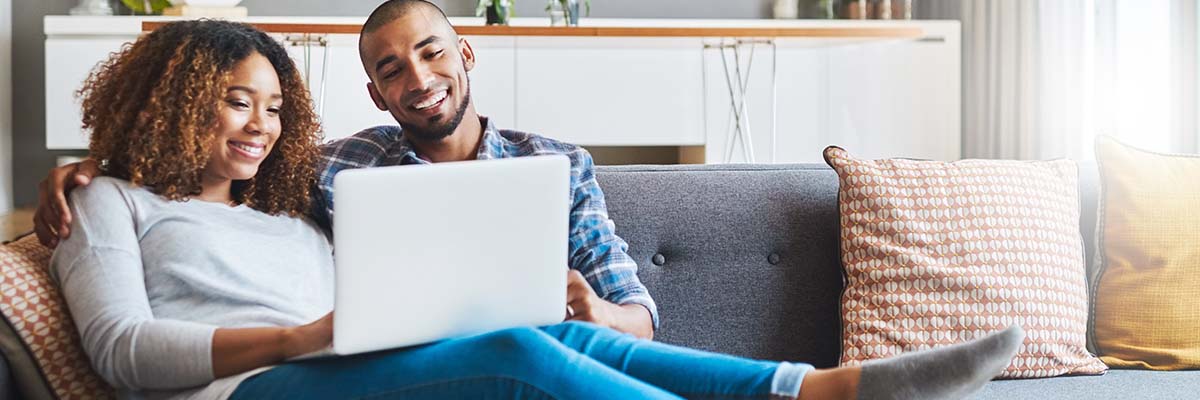 Couple sitting on couch with laptop