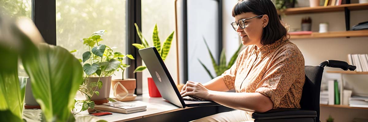 person in wheelchair at desk with tablet device