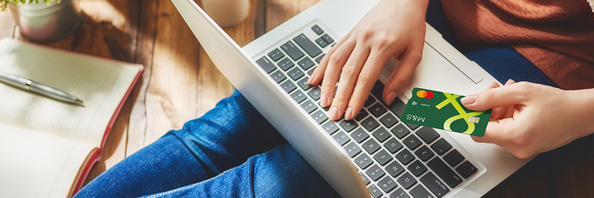 Person sat on floor with laptop holding Credit Card