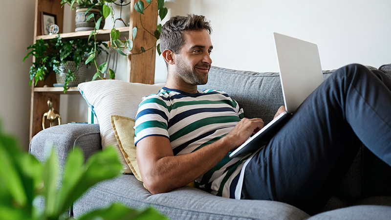 Person lying on sofa with laptop