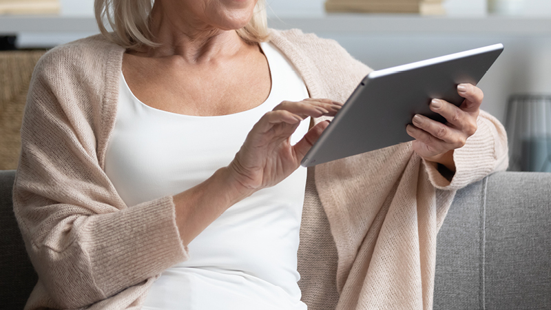 A lady sat on a sofa, using a tablet