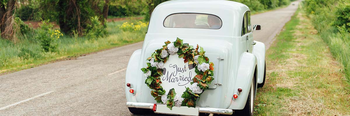 A wedding car with the words just married and a flower wreath on the back